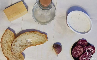 Подготовьте ингредиенты. Разогрейте сковородку, очистите чеснок. Колбасу нарежьте на полоски.