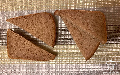 Кусочки черного хлеба разрежьте на треугольники. Выложите сверху начинку из салатника.