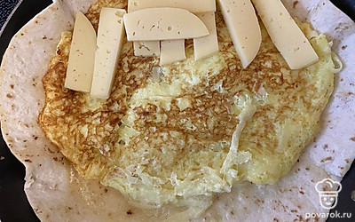 Переверните, нарежьте сыр и разложите на одну половину.