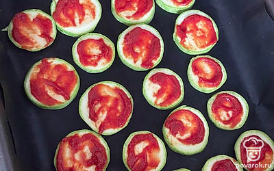 Выкладываем на противень, застеленный антипригарным ковриком или бумагой. Смазываем каждый ломтик томатной пастой.