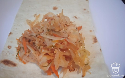 Из листа лаваша нарежьте полоски шириной 10 сантиметров. На каждую полоску положите немного тушеной капусты. 