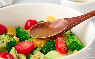 Выложите в салатник брокколи, помидоры черри и дольки апельсина. Полейте их заправкой. 