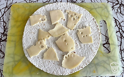 На тортилью хаотично выложите куски сыра.