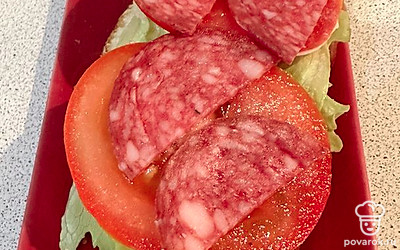 Сырокопченую колбасу нарезаем кружочками. Посыпаем итальянскими травами.