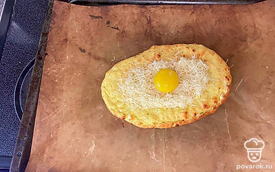 Достаньте из духовки, насыпьте сыр в выемку, в центр вылейте желток. Отправьте в духовку на несколько минут, чтобы сыр расплавился.