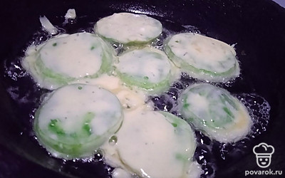 Обваляйте в полученном кляре зеленые помидоры. Выложите на сковороду с разогретым растительным маслом.