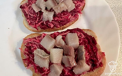 Свекольно-сырную смесь выкладываем на хлеб. Сверху украшаем соленой сельдью.