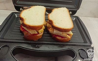 Накрываем начинку ломтиками хлеба и выкладываем в мультипекарь, выпекаем сэндвичи 3 минуты. 