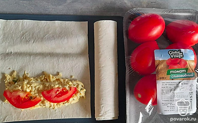 Разрезать листы лаваша, выложить на край начинку, сверху положить ломтики томатов и свернуть в трубочку.