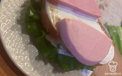 Смазать майонезом, выложить дольки колбасы.