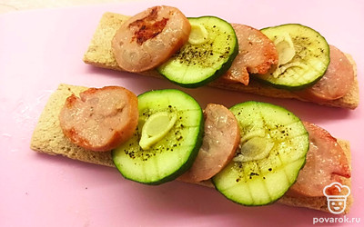 Выложите поочередно жареную колбасу и огурец на хлебцы (как на фото).