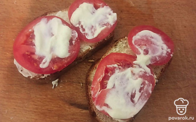 Выложите на тосты кольца помидора, сверху намажьте их сметаной. Посолите по вкусу.