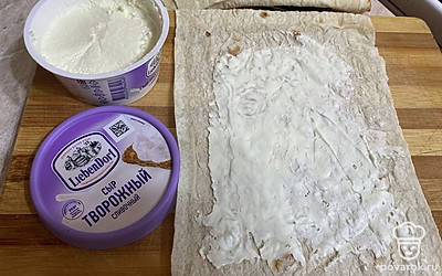 Лист лаваша делим на 4 части и каждую смазываем сыром, не доходя немного до края.