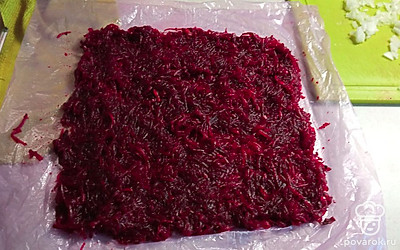 Отварную свеклу натираем на терке. На пищевую пленку выкладываем в виде прямоугольника. Смазываем майонезом.