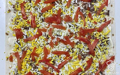 Выложите тунца, сверху натертые на крупной терке яйца и порезанный помидор.