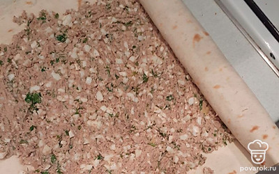 Разверните лаваш. Небольшими порциями выкладывайте на него начинку, равномерно распределяя её вилкой. Скрутите рулет. 