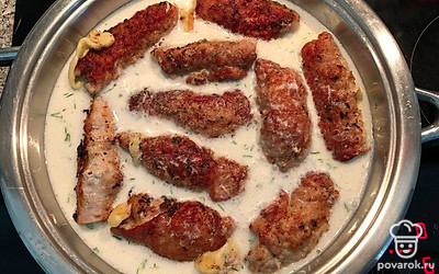 В небольшой таре смешайте мелко порезанный чеснок и сметану, в полученную смесь окуните рулеты, переложите в сковороду, добавьте немного воды, около 200 мл, и тушите на медленном огне, накрыв крышкой.