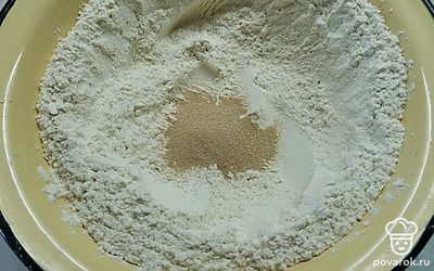 В муку высыпать сухие дрожжи и хорошо перемешать. Сделать углубление. 