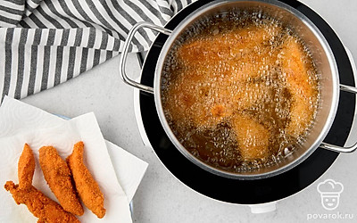 Налейте в сотейник рафинированное растительное масло, дайте ему хорошо разогреться на среднем огне. Выложите в горячее масло запанированные заготовки и обжарьте все стрипсы в течение 2-3 минут со всех сторон до золотистой корочки. 