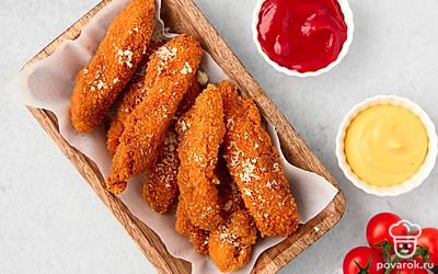 Подайте к обжаренным куриным стрипсам сырный соус и кетчуп. Посыпьте сыром.