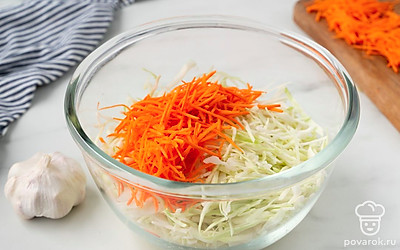 Натрите морковь на крупной терке. Положите измельченную морковку в одну миску с капустой.