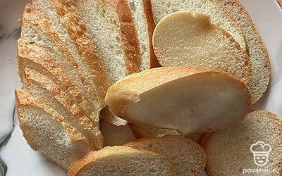 Порционно нарежьте багет. И обязательно подсушите его.