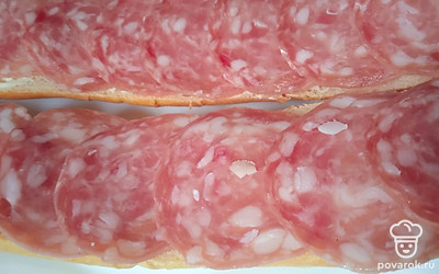 Выложите сверху нарезанную колбасу.