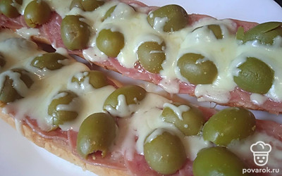 Сыр моцарелла натрите на терке. Распределите поверх оливок. Поставьте на две минуты в микроволновку.