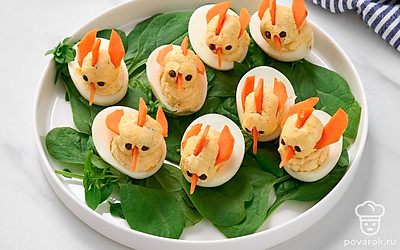 Застелите тарелку для подачи шпинатными листьями. Расставьте на них закуску «Цыплята» из плавленых сырков. 