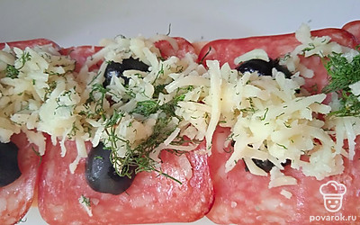 Положите поверх багета нарезанную колбасу, маслины и чесночную смесь. Запекайте 10 минут при температуре 220 градусов.