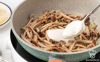 Положите к опятам сметану. Потушите все, помешивая, 2-3 минуты. Всыпьте муку и прогрейте ее с опятами и сметаной, постоянно помешивая, 1-2 минуты. Уберите сковороду с огня, всыпьте в нее половину тертого сыра и размешайте. 