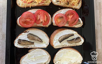Выложить хлеб на противень, смазать хлеб майонезом. Выложить сверху шпроты, затем помидоры и сыр. Запекать в духовке при 180 градусах 15 минут.