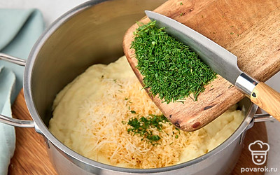 Всыпьте в картофельное пюре половину сыра. Добавьте туда же зелень и перемешайте.