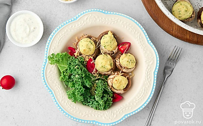 Подайте начиненные шампиньоны под шубой на салатных листьях вместе с помидорами черри.