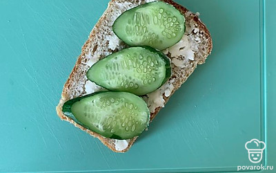 Намазать плавленый сыр на хлеб и выложить огурец.