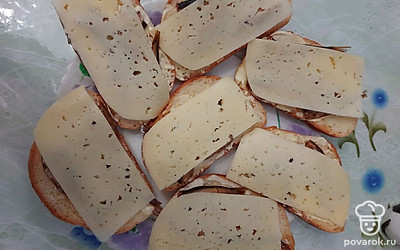 Сверху на каждый бутерброд кладем по 2 ломтика сыра так, чтобы он полностью закрывал шпроты.