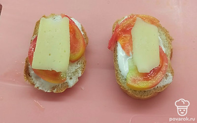 Поверх помидора выкладываем ломтики сыра. 