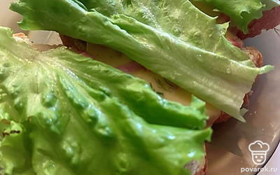 Кладем по одному листу на каждый бутерброд и по кружочку вареного яйца.