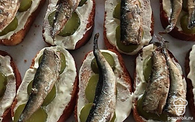 Батон намазать майонезом, положить огурцы и сверху шпроты. 
Все, наша закуска готова.