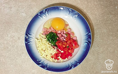 Зелень помойте и мелко нарежьте, положите в глубокую тарелку. К зелени разбейте яйцо, положите сыр, колбасу и помидор. Посолите и поперчите, хорошо перемешайте.