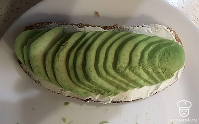 Намажьте на хлеб творожный сыр и положите авокадо.