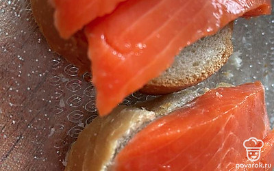 Режем рыбку и кладем сверху багета, следом огурчик.