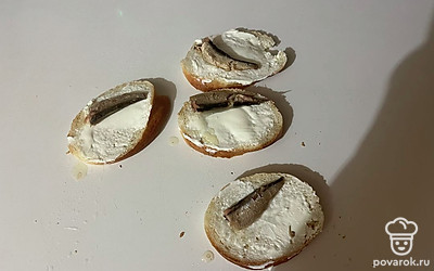 Поверх творожного сыра выложите шпроты. Они должны занимать примерно 80% всей поверхности каждого ломтика хлеба.