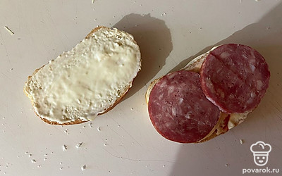 Поверх одного из ломтиков хлеба выложите колбасу.