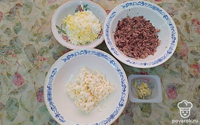 Отварить яйца и натереть на крупной терке. Натереть там же плавленный сыр. Тунец размять вилкой. Чеснок натереть на мелкой терке. 