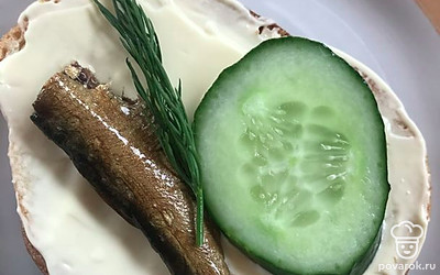 Разрежьте огурцы. Выложите на хлеб шпроты, зелень, огурцы.