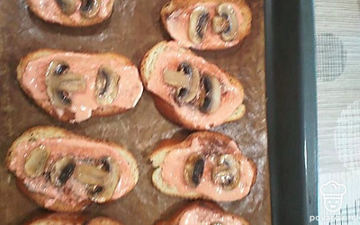 Каждый кусочек батона промажьте соусом и майонезом, выложите шампиньоны и посыпьте тертым сыром.
