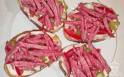 На обжаренный хлеб выложите несколько кусочков помидора. На каждый ломтик, сверху помидоров положите нарезанный болгарский перец. На перец выложите колбасу.