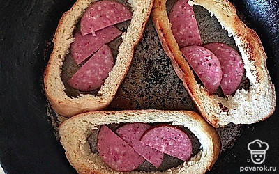 Из хлебных ломтиков вырежьте мякиш, чтобы получилась своеобразная «рамка». Обжарьте хлеб с двух сторон на разогретом масле. О внутрь положите кусочки колбасы и поджарьте буквально 30 секунд.