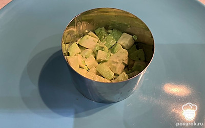 Смешайте авокадо с лимонным соком и уложите на дно сервировочного кольца.